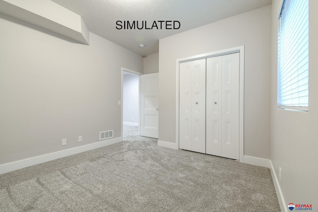 unfurnished bedroom with a closet, carpet, visible vents, and baseboards