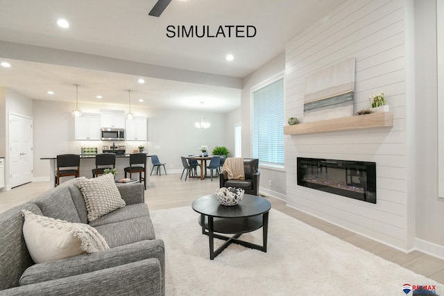 living room with a large fireplace, baseboards, light wood-style flooring, and recessed lighting