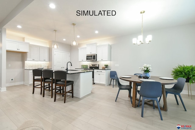 kitchen with appliances with stainless steel finishes, dark countertops, a kitchen island with sink, and backsplash