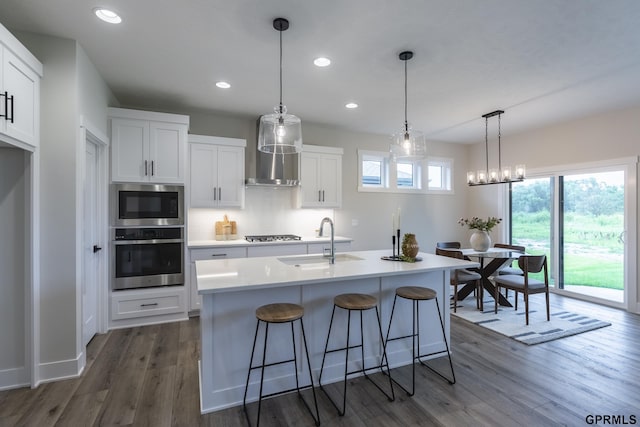 kitchen featuring stainless steel appliances, a sink, white cabinets, light countertops, and dark wood finished floors