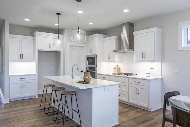 kitchen with white cabinets, wall chimney exhaust hood, stainless steel appliances, and a sink