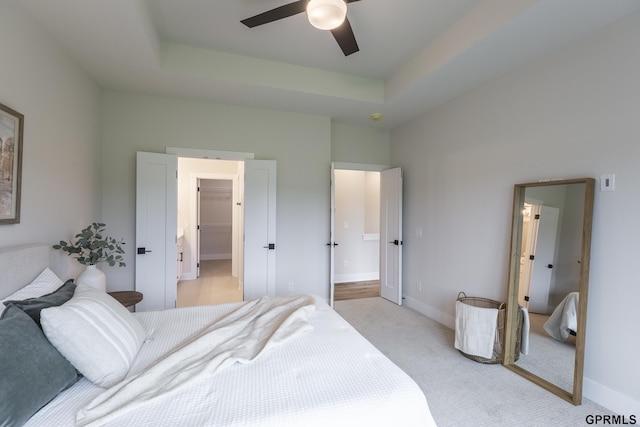 bedroom with baseboards, a spacious closet, a tray ceiling, and light colored carpet