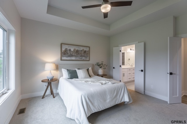 bedroom with light carpet, multiple windows, a raised ceiling, and visible vents