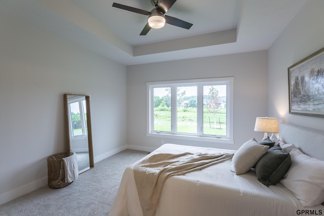 bedroom featuring carpet, a tray ceiling, ceiling fan, and baseboards