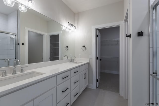 full bathroom with a walk in closet, a sink, and a shower stall