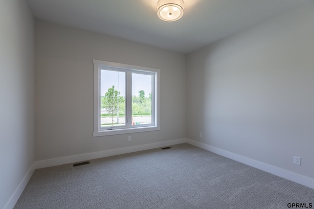 empty room with light colored carpet, visible vents, and baseboards