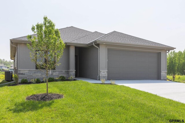 view of front of home featuring a front lawn, a garage, and central AC