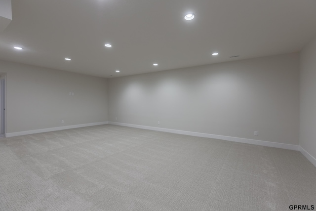 empty room featuring light carpet, baseboards, and recessed lighting