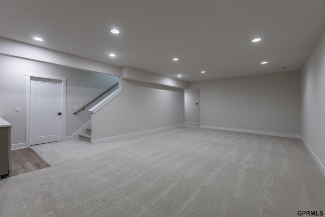 finished below grade area featuring recessed lighting, light colored carpet, baseboards, and stairs