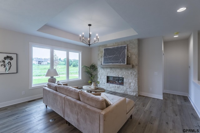 living area with a tray ceiling, a fireplace, and wood finished floors