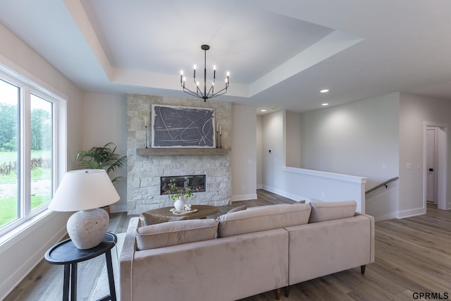 living room featuring a tray ceiling, a fireplace, baseboards, and wood finished floors