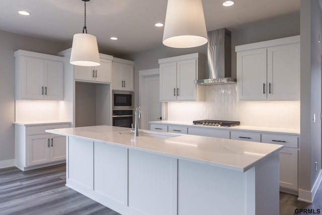 kitchen featuring appliances with stainless steel finishes, white cabinetry, and wall chimney range hood