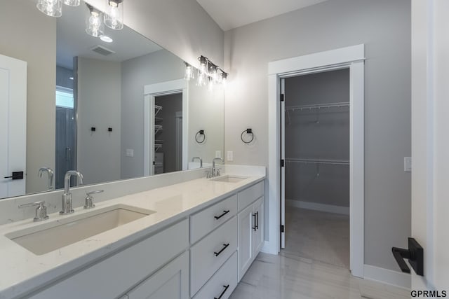 bathroom with visible vents, a sink, a spacious closet, and double vanity