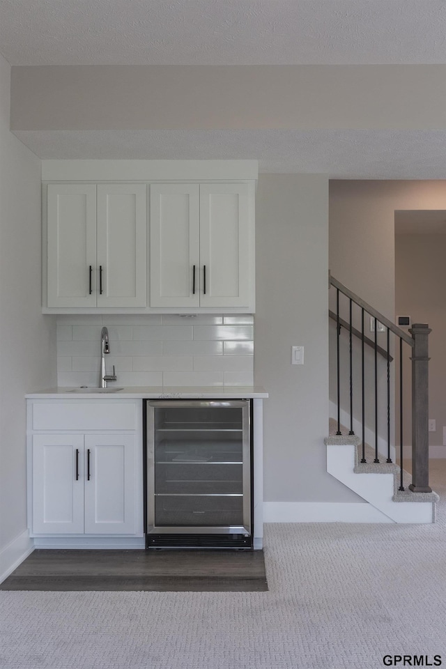 bar with stairs, wine cooler, backsplash, and a sink