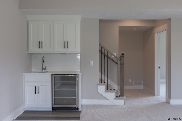 bar with visible vents, stairway, backsplash, a sink, and beverage cooler