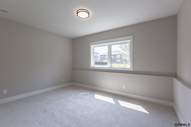 spare room featuring baseboards, visible vents, and light colored carpet