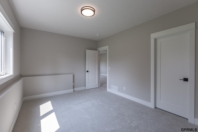 unfurnished bedroom featuring baseboards, visible vents, and light colored carpet