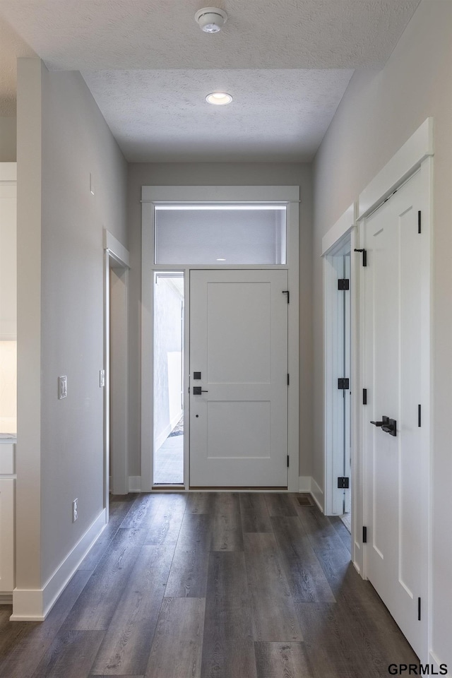 entryway featuring baseboards, dark wood finished floors, and a textured ceiling