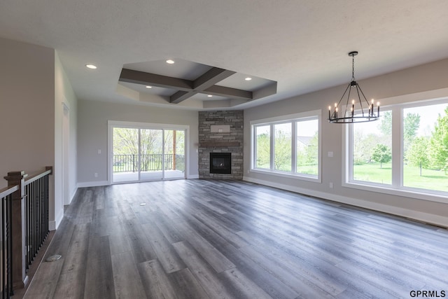 unfurnished living room with coffered ceiling, baseboards, dark wood finished floors, and a wealth of natural light