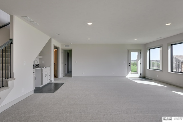 unfurnished living room featuring light carpet and sink