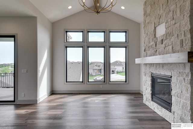 unfurnished living room with a healthy amount of sunlight, a stone fireplace, and a notable chandelier