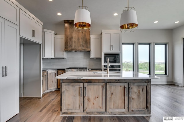 kitchen with hanging light fixtures, a kitchen island with sink, and hardwood / wood-style flooring