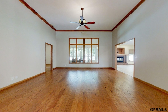 unfurnished living room featuring light hardwood / wood-style floors, ornamental molding, a brick fireplace, and ceiling fan