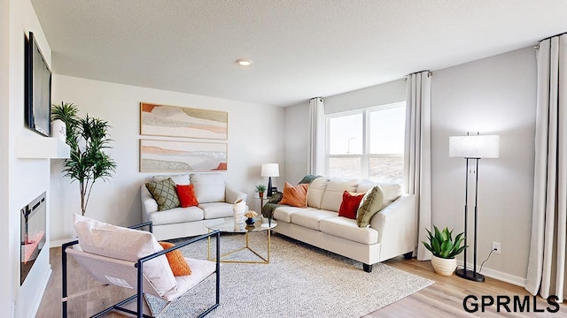 living room with light wood-type flooring, a fireplace, and a textured ceiling