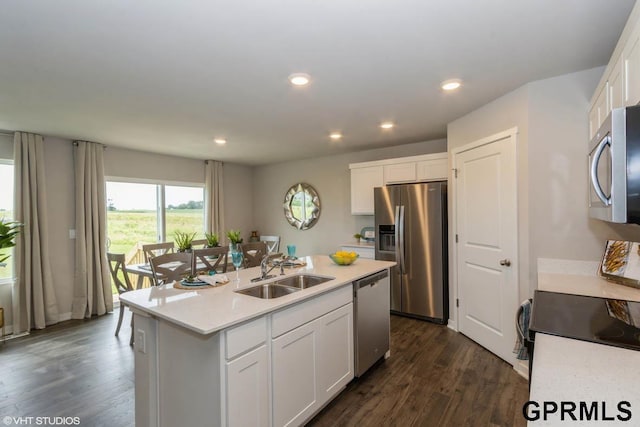 kitchen featuring stainless steel appliances, white cabinetry, sink, dark wood-type flooring, and a kitchen island with sink