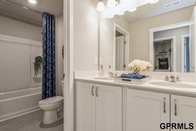 full bathroom featuring a sink, visible vents, toilet, and double vanity