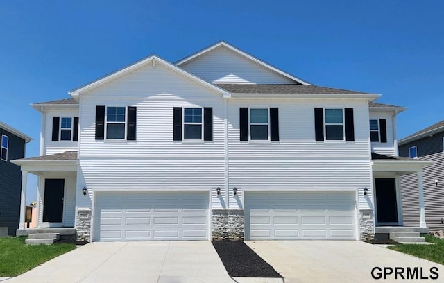 view of front facade featuring a garage, stone siding, and driveway