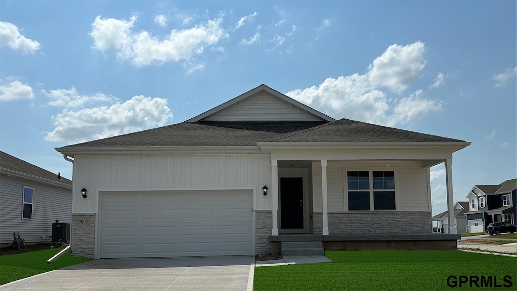 view of front facade with cooling unit, a garage, covered porch, and a front yard