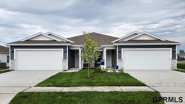 view of front of house with central AC, a garage, and a front lawn