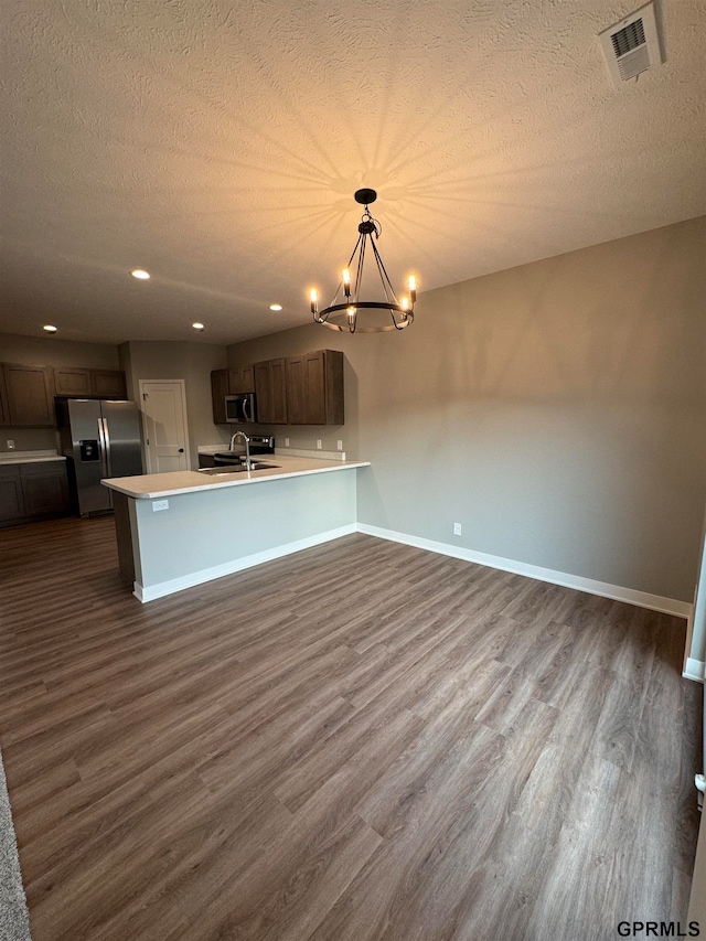 kitchen featuring light countertops, dark wood-style floors, stainless steel appliances, baseboards, and visible vents