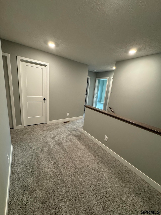 empty room with baseboards, a textured ceiling, visible vents, and carpet