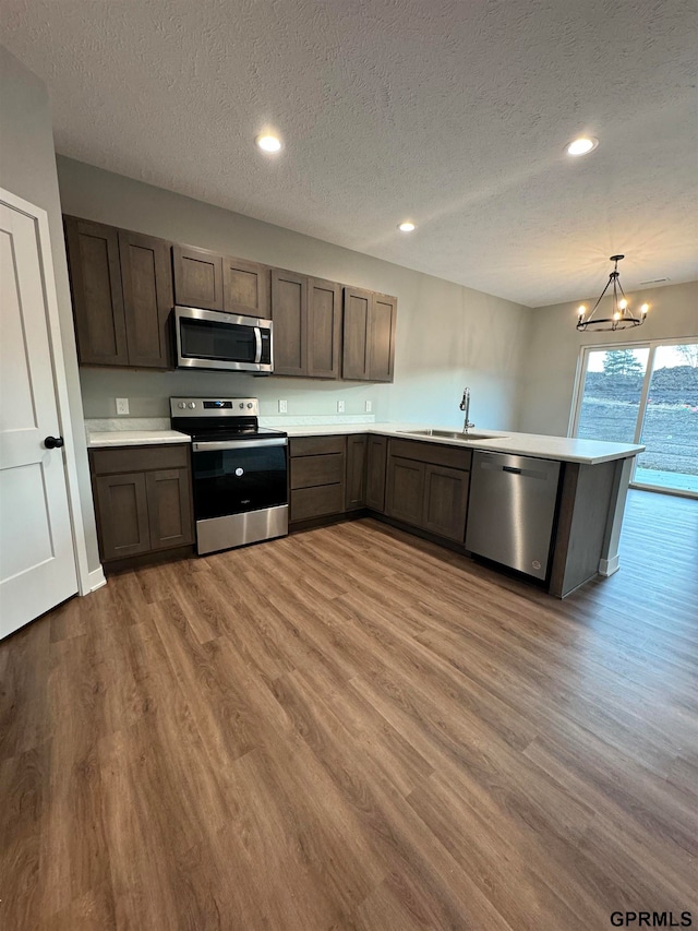 kitchen featuring light countertops, a sink, wood finished floors, and appliances with stainless steel finishes