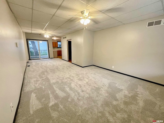 empty room with ceiling fan, light carpet, and a drop ceiling