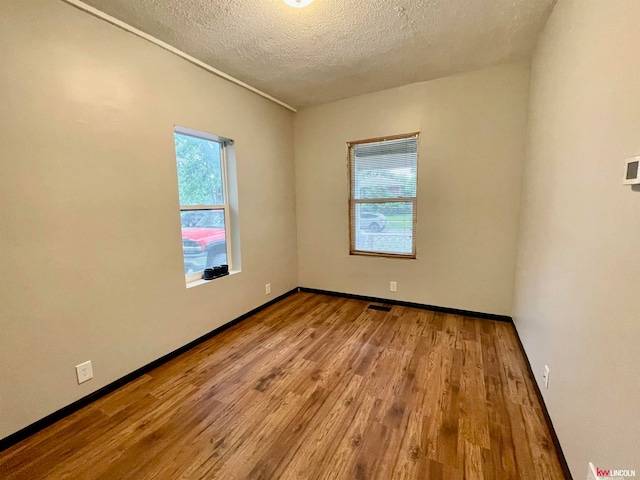 unfurnished room featuring a textured ceiling, wood-type flooring, and a wealth of natural light