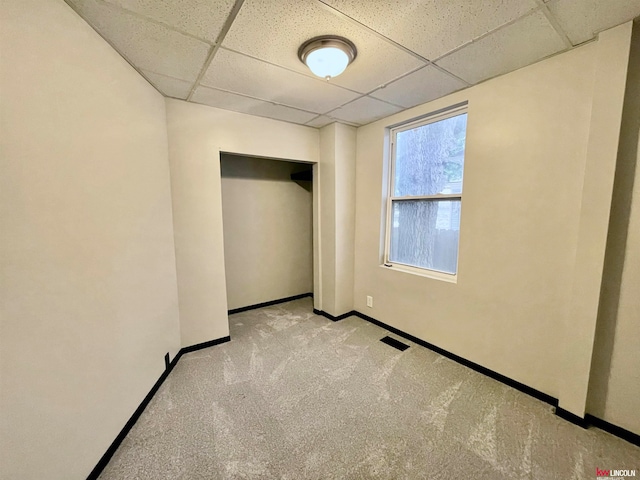 carpeted empty room featuring a drop ceiling