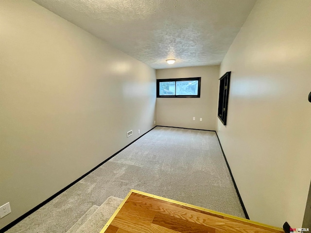 carpeted spare room with a textured ceiling