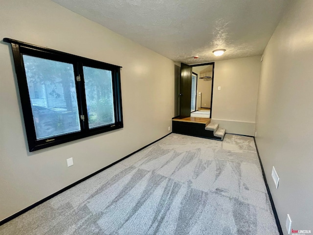 carpeted empty room with a textured ceiling