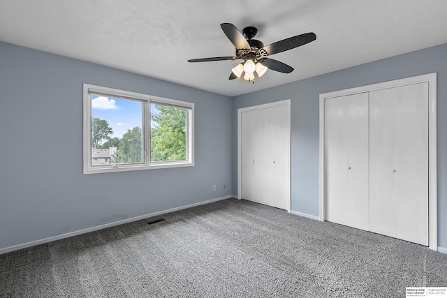 unfurnished bedroom featuring two closets, ceiling fan, and carpet floors