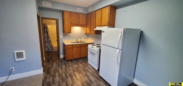 kitchen with dark wood-type flooring, sink, white appliances, and heating unit