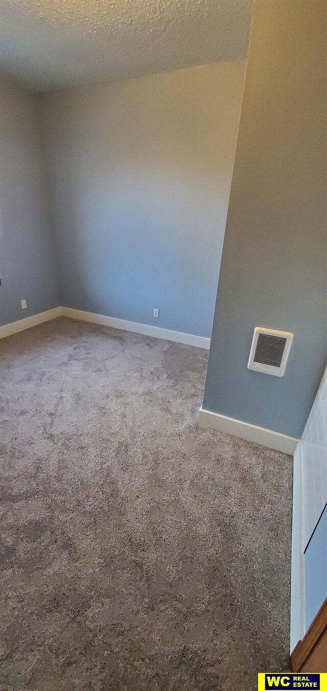 unfurnished room featuring a textured ceiling and carpet floors