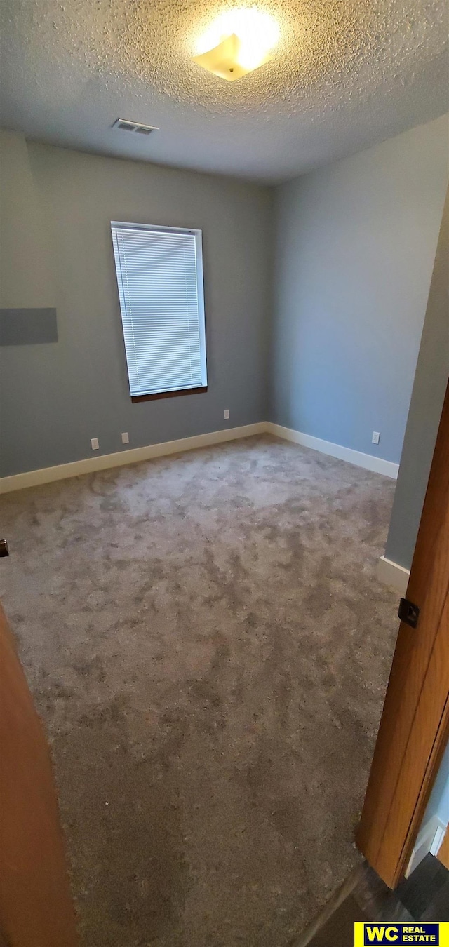 empty room with a textured ceiling and carpet floors