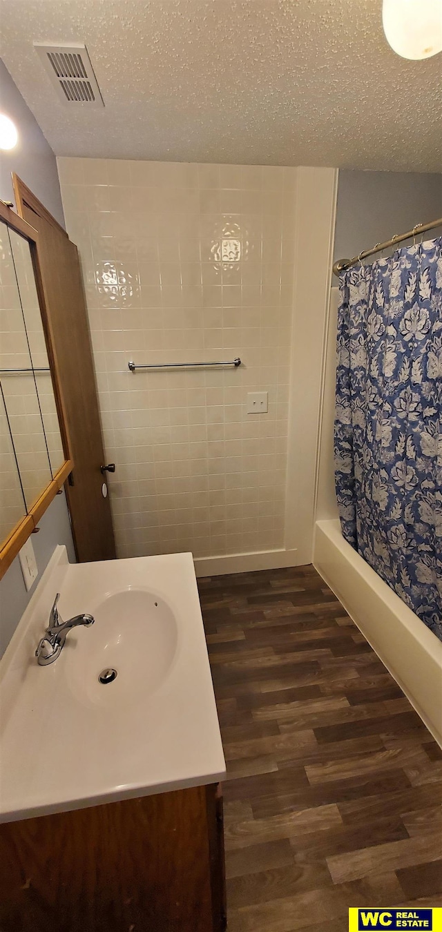 bathroom featuring hardwood / wood-style floors, a shower with curtain, and a textured ceiling