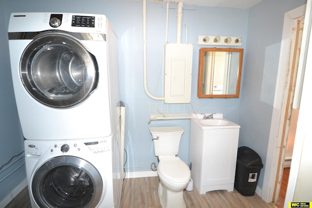 clothes washing area featuring light wood-type flooring, stacked washer and clothes dryer, and sink