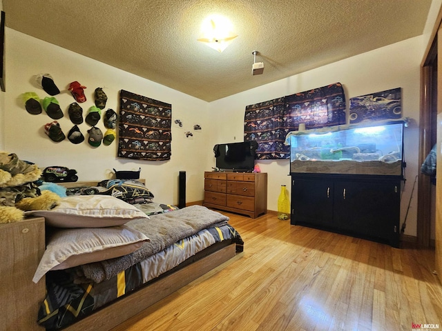bedroom with lofted ceiling, wood finished floors, and a textured ceiling