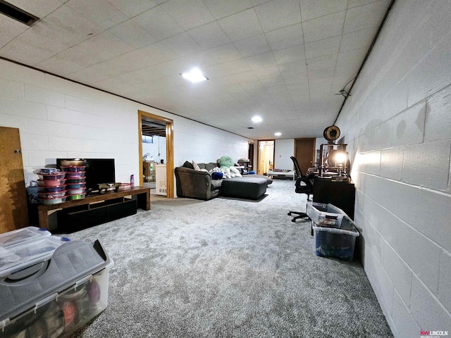 carpeted living area featuring visible vents and concrete block wall
