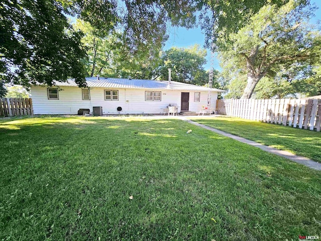 rear view of house with a fenced backyard, central air condition unit, and a yard